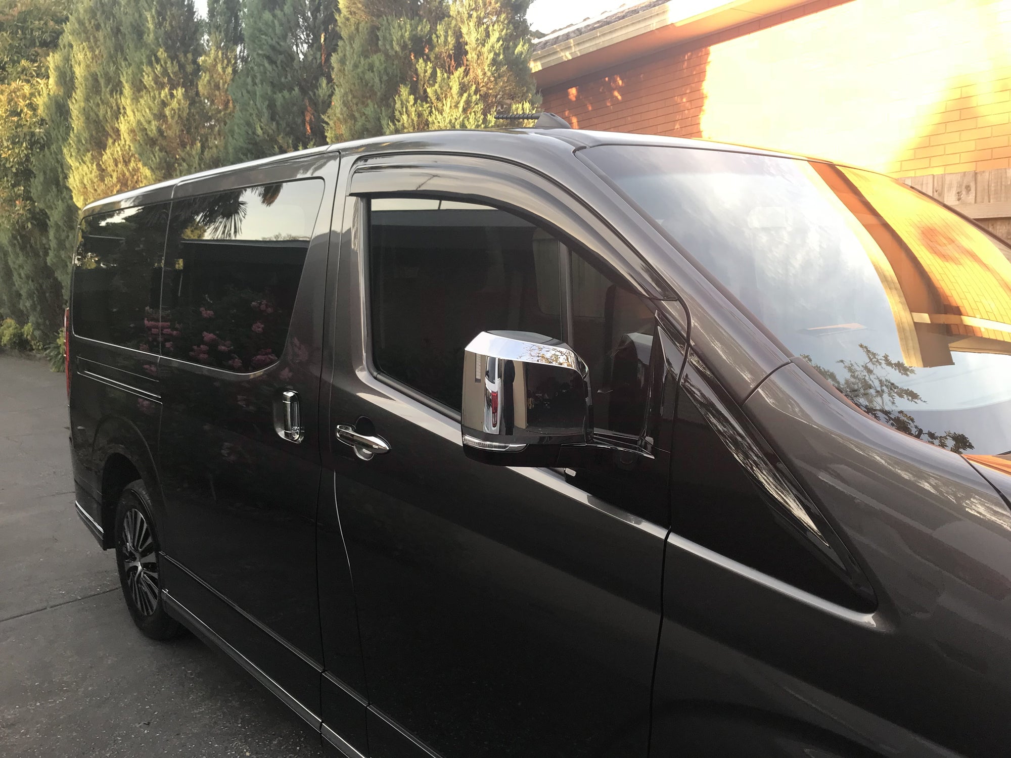 A black Toyota Granvia parked in front of a building with a brick facade.