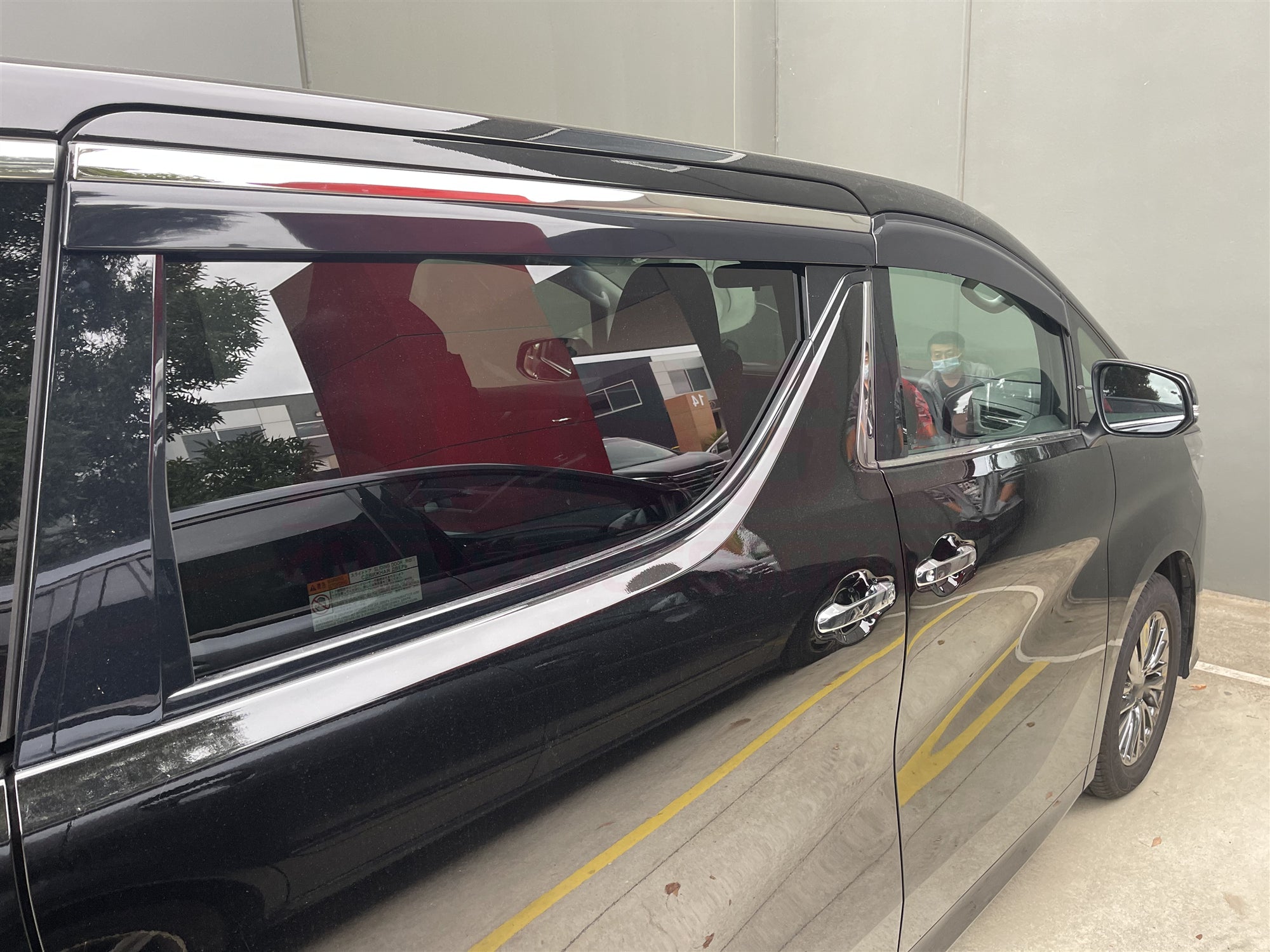 Side view of a Toyota Alphard parked in an indoor carpark.