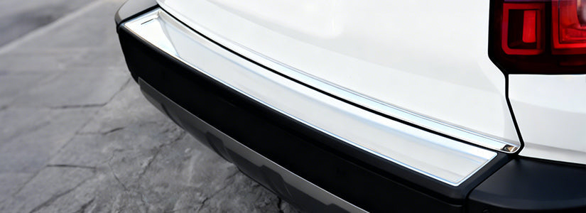 Zoomed in photo of a rear bumper step plate attached to a white car