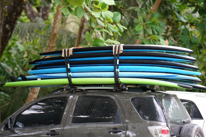 Canoes tied to roof racks on top of an SUV with trees in the background
