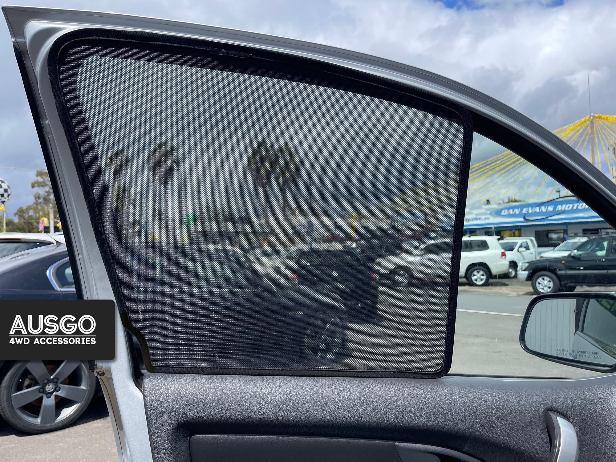 A sun shade attached to the passenger seat window of a car.