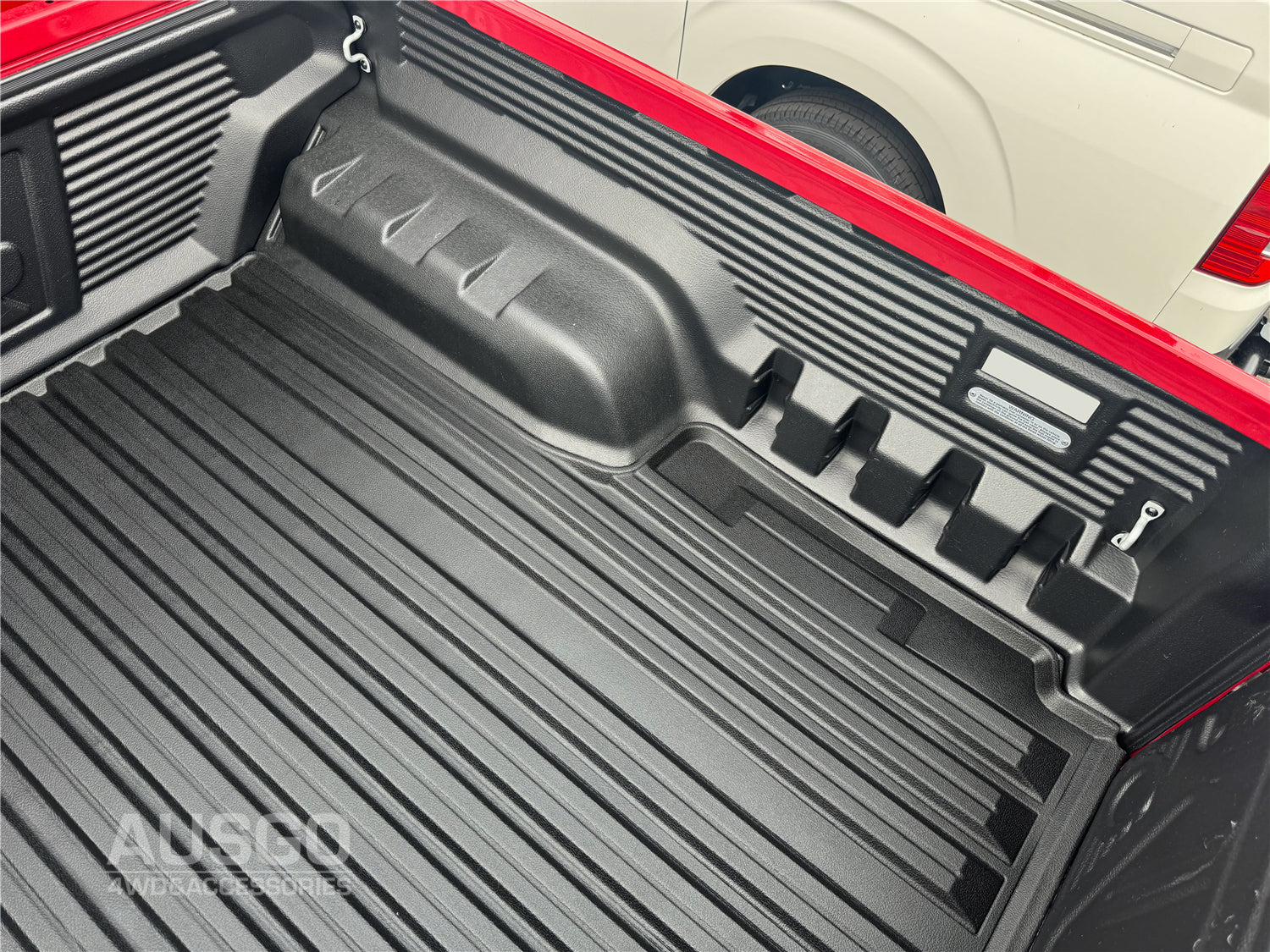 A black ute mat attached in the back of a red ute.