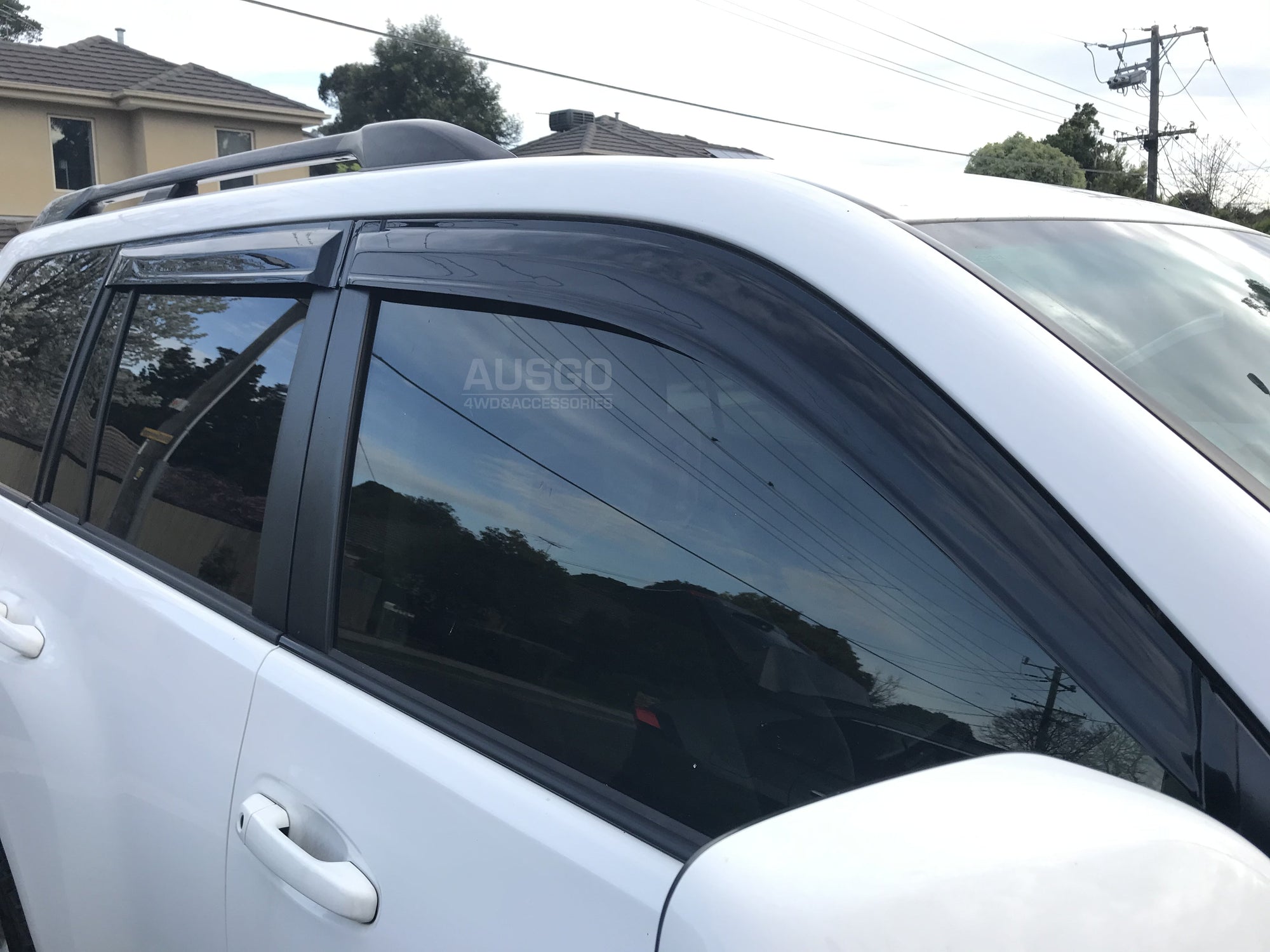 Aide view of a white Toyota Land Cruiser with sun shades attached to the windows.