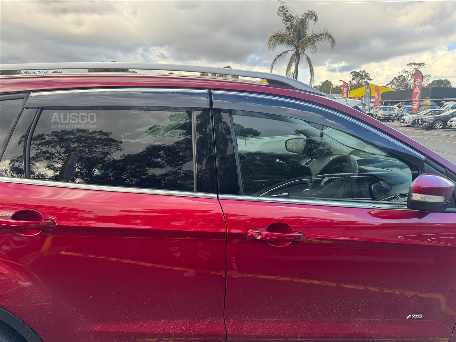 Side view of a red Ford Escape with black weather shields attached to the windows. 