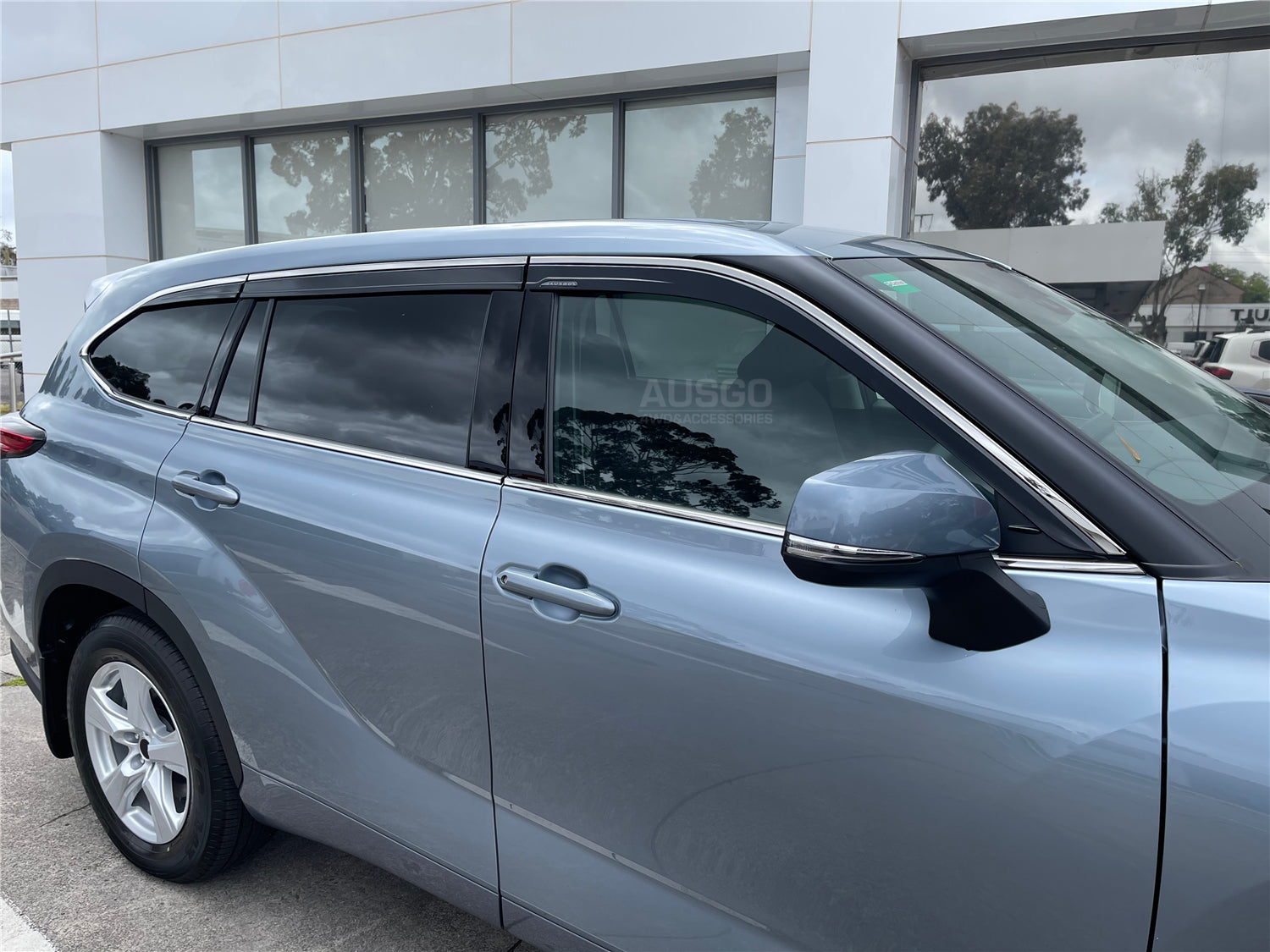 Side view of a grey Toyota Kluger parked in front of a white building